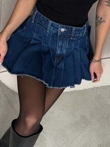 Minigonna a pieghe in denim blu scuro con orlo a frange e vita alta alla moda