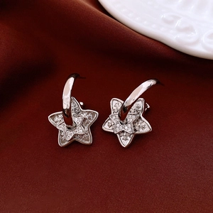 Macro detail of silver star earrings with zircon inlay on a red velvet background