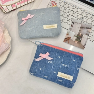 Detailed view of light and dark blue denim coin purses with pink ribbon embroidery