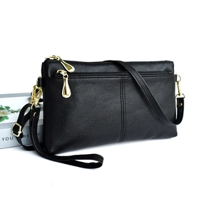 Close-up of black litchi pattern leather shoulder bag with gold metal zipper details