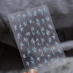 Macro shot of TO-5330 nail art stickers with blue bamboo leaves and gold metallic details