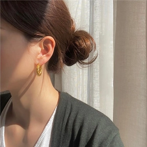 Elegant 925 sterling silver gold twisted hoop earrings worn by a model in soft light