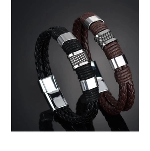 Detail of woven leather bracelets in black and brown with textured magnetic metal buckles