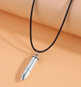 Close-up of a silver bullet pendant necklace with a black cord on orange background