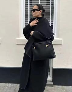 Street style view of a long black wool coat paired with a luxury leather handbag