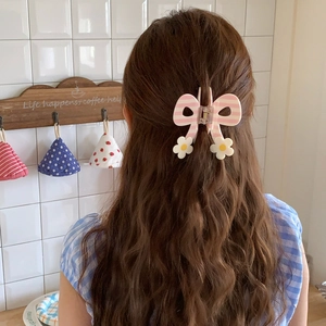 Detail of pink and white striped butterfly hair claw with floral accents on hair