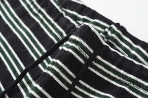 Close-up of black and green striped knit fabric showing the waist drawstring and texture