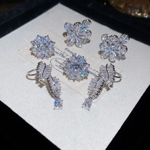 Macro shot of silver zircon flower ear clips with sparkling stones on soft fabric