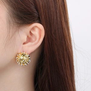 Detail of gold dome earrings featuring rows of white pearls worn by a model