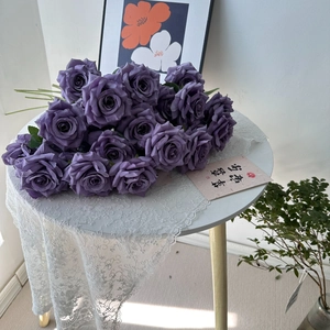 Close-up of deep purple artificial roses with silk texture on a white lace tablecloth