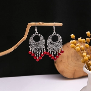 Détail de boucles d'oreilles bohèmes argentées avec perles rouges sur branche