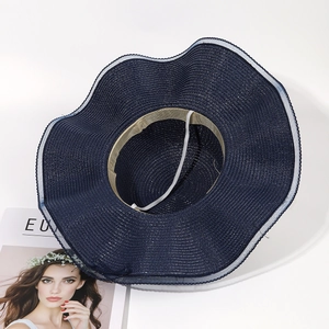 Detail of navy blue straw sun hat showing interior sweatband and white mesh trim edge
