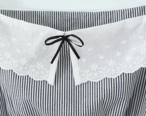 Detail der bestickten Spitzenbordüre und schwarzen Schleife am gestreiften Crop-Top