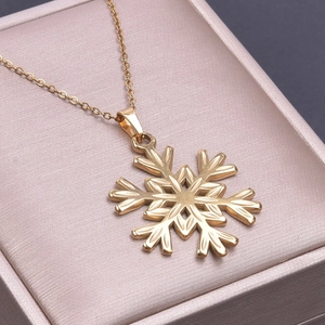 Macro shot of gold snowflake pendant with delicate cross chain on luxury jewelry box