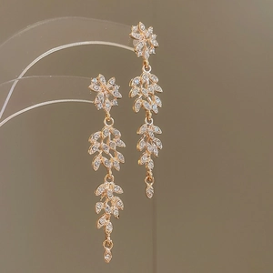 Détail de boucles d'oreilles feuilles en or rose avec cristaux et pampilles élégantes