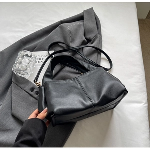 Minimalist black lychee leather handbag displayed on a grey blazer for office styling