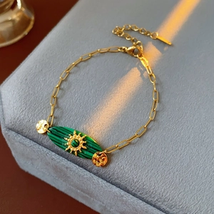 Détail d'un bracelet vintage en chaîne dorée avec pierre de malachite et motif soleil