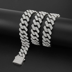 Iced out silver Cuban link chain necklace with sparkling crystals on a black pedestal