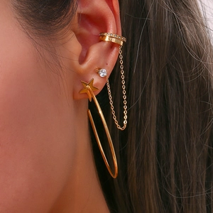 Macro view of gold star earring set with rhinestone stud and chain ear cuff on model