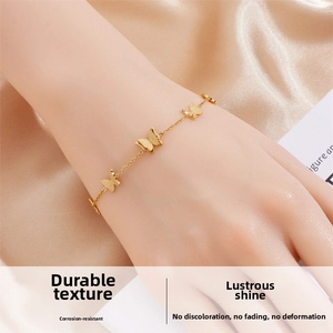 Golden stainless steel chain bracelet with butterfly charms on silk background