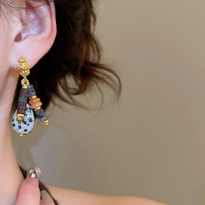 Close-up of ethnic beaded tassel earrings with Dalmatian stone worn by model