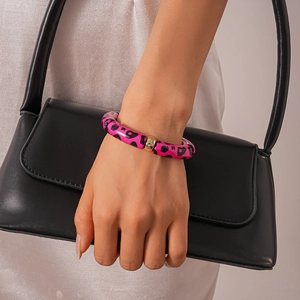 Close-up of pink leopard print acrylic bracelet with gold metal buckle on female wrist