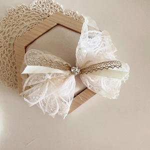 Détail du nœud en dentelle à paillettes beige avec un cœur en strass étincelant