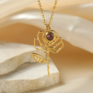 Macro detail of 18k gold plated rose pendant with inlaid purple gemstone on satin