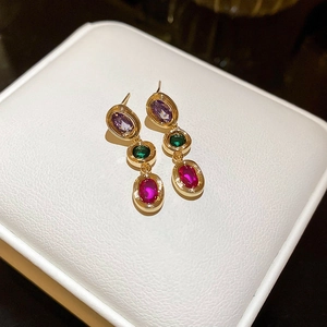 Macro shot of three-tier drop earrings with purple green and red oval crystals