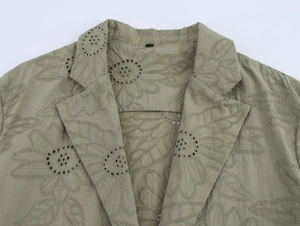 Close-up of sage green blazer with floral eyelet embroidery and notch lapel details