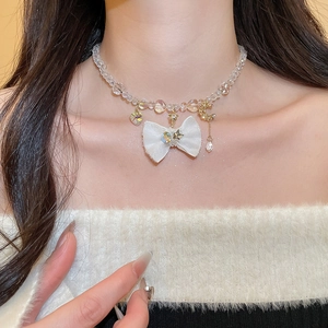 Close-up of white fabric bow necklace with heart, star, and moon crystal pendants