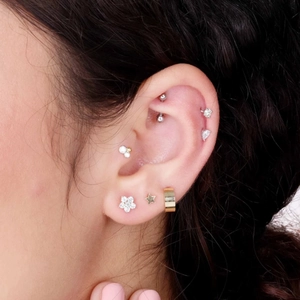 Close-up of stacked butterfly and flower earrings with rhinestones on ear