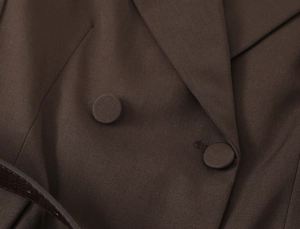 Close-up of deep brown twill fabric with matching fabric-covered buttons and leather belt