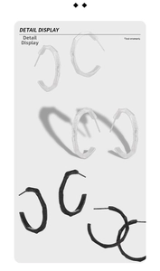Detail view of C-shaped geometric earrings with textured silver and black finishes