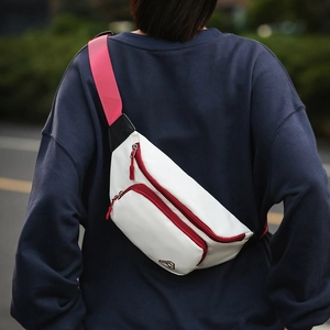 Weiße Crossbody-Tasche aus Nylon mit roten Reißverschlüssen und rosa Gurt am Modell