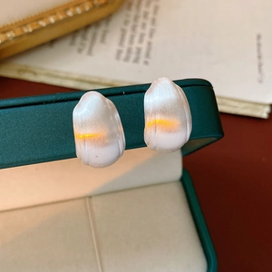 Macro shot of white cat eye stone square earrings on a dark green leather jewelry box
