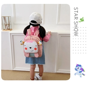 Vista trasera de una linda mochila de oveja rosa para niña pequeña en una habitación blanca.