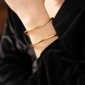 Gros plan d'un bracelet manchette doré ondulé et minimaliste porté au poignet