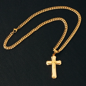 Macro shot of gold-plated double-layer cross pendant on Cuban chain over black leather
