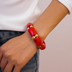 Detail of red marble acrylic cylindrical beads with gold spacer accents on bracelet