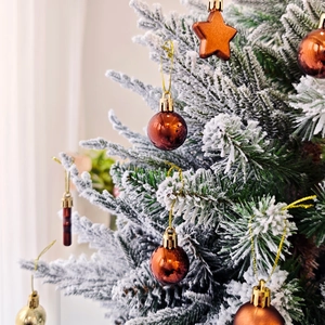 Gros plan d'ornements festifs en cuivre et or sur des branches de sapin enneigées