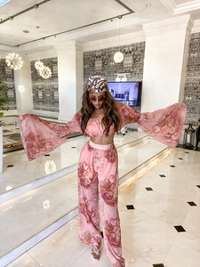 Detail of pink floral chiffon off-shoulder top and wide-leg trousers on a model