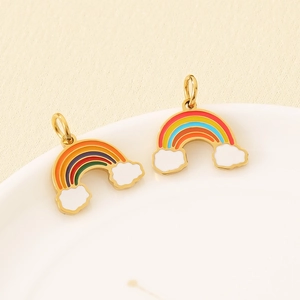 Detail of two 18K gold-plated rainbow cloud charms in a white ceramic dish