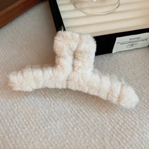 Close-up of cream plush cross hair claw clip with fluffy texture and French style detail