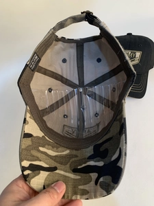 Dettaglio del cappellino da baseball mimetico con etichetta 100% poliestere e cinturino regolabile