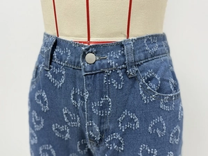 Close-up of blue straight jeans with heart-shaped distressed texture on fabric
