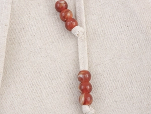 Dettaglio del tessuto di lino e cotone beige con coulisse e decorazioni di perline