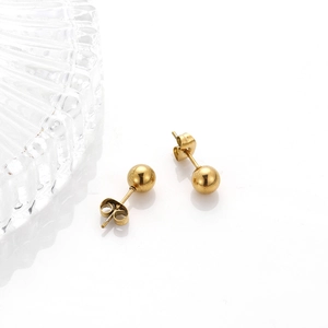 Pendientes de bola en acero inoxidable dorado pulido sobre una superficie blanca brillante