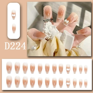 Detailed view of D224 nude gradient press-on nails with white bows and 3D ribbon accents
