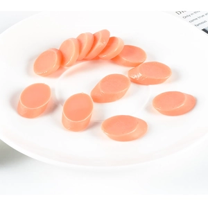 Detailed view of pink oval miniature food ham slices arranged on a white ceramic plate